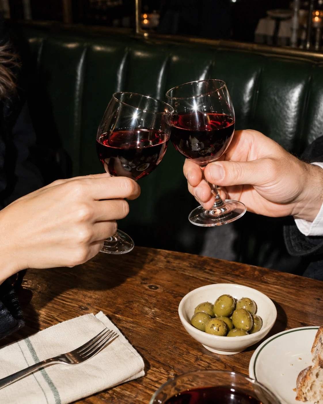 Deux verres de vin rouge levés au-dessus d’une table de bistrot